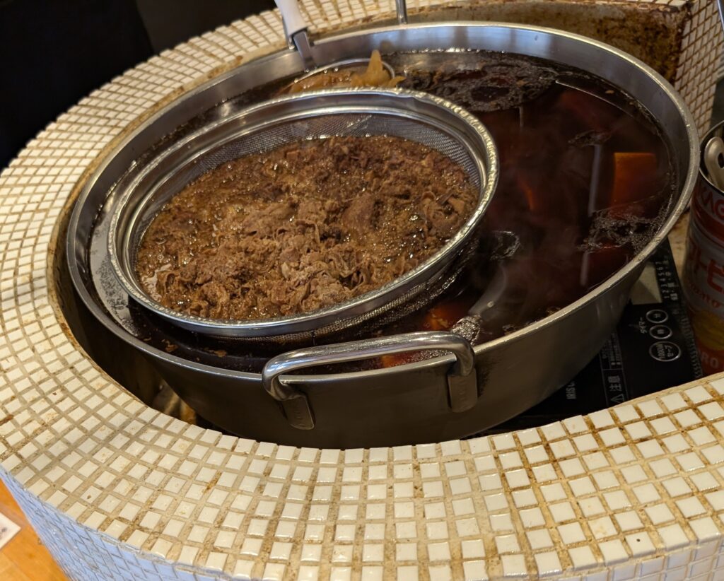 食堂うめぼし天神南のカウンター前で肉豆腐を煮込む大鍋