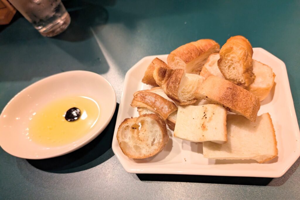 大衆イタリアンうめぼしのお通しのパン。クロワッサンや明太フランスなど数種類とオリーブオイル