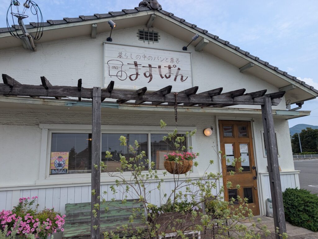 ますぱんの外観。白い建物の前に花とベンチが置かれている