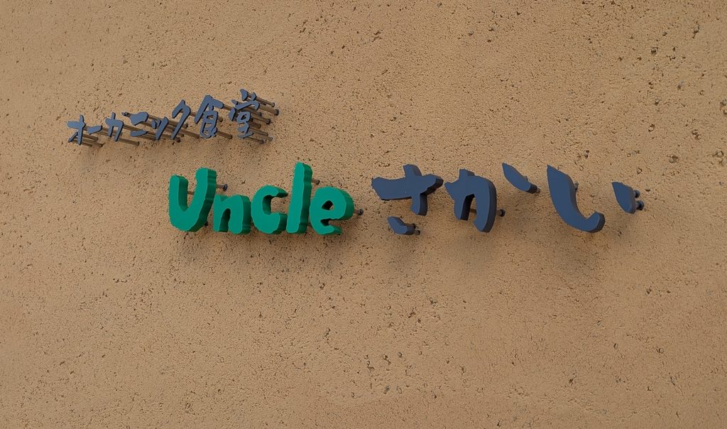 外壁に取り付けられた「オーガニック食堂 Uncleさかい」のロゴサイン