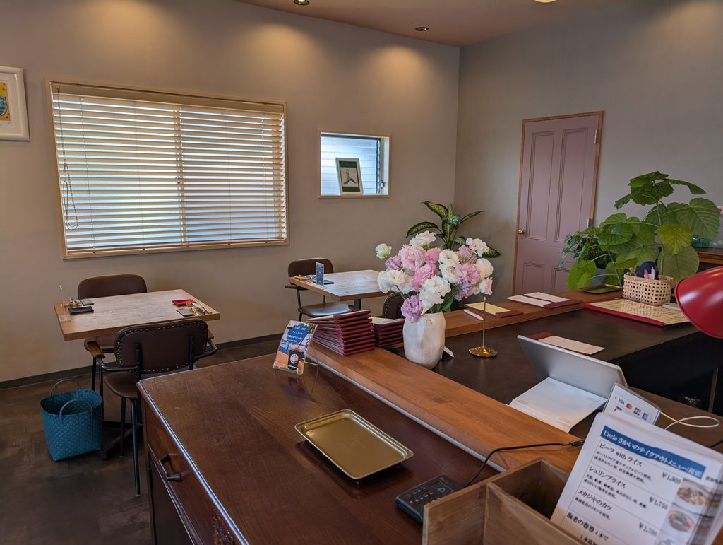 Uncleさかいの店内。テーブル席と、生花が飾られたカウンター