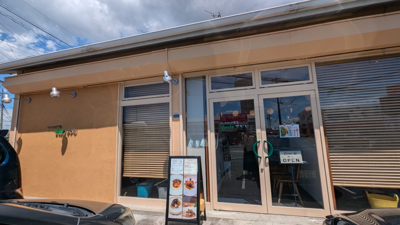 オーガニック食堂Uncleさかいの外観。オレンジ色の外壁とガラス張りの入口、店頭にメニューの立て看板