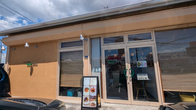 オーガニック食堂Uncleさかいの外観。オレンジ色の外壁とガラス張りの入口、店頭にメニューの立て看板